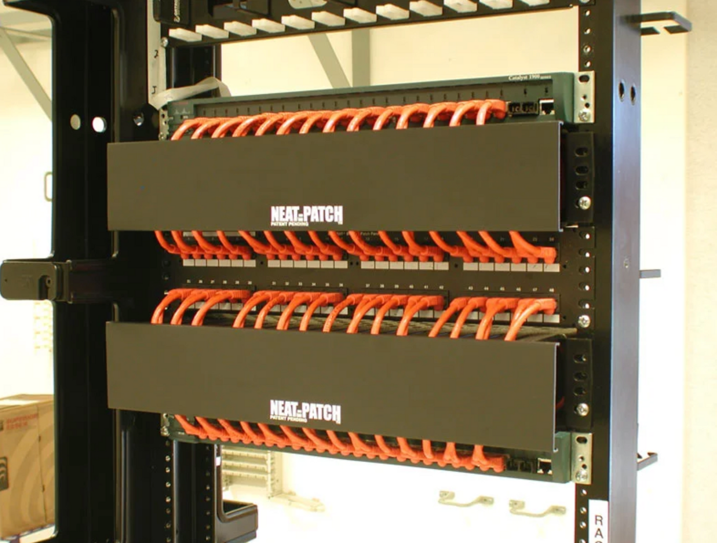 Orange patch cables routed in uniform loops to maintain bend radius inside Neat-Patch managers
